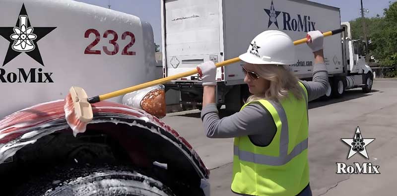 Truck fender being pressure washed with Bumper-to-Bumper fleet wash soap — removing road grime and concrete residue